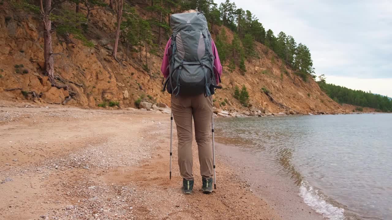 徒步旅游探险。无法辨认的徒步女游客背着背包在湖边散步。背包客女人享受美丽的海滩景色，后视图女人享受徒步旅行旅游积极的假期视频素材