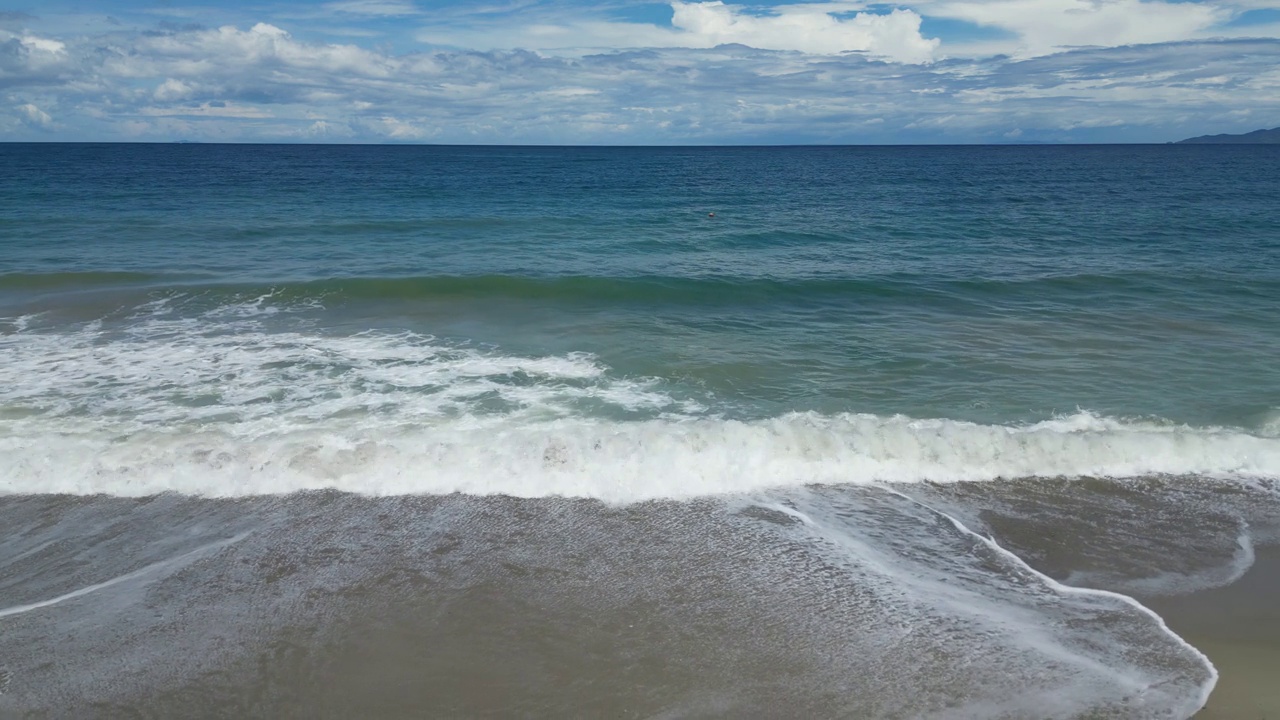宽阔的海浪翻滚在沙滩的海岸线上，为游客们提供便利视频素材