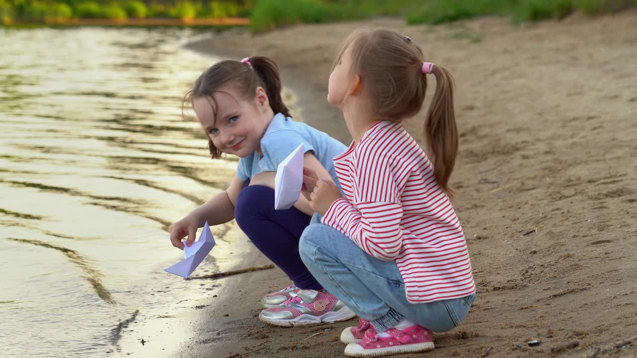 孩子们在夏日公园的河上玩纸船，在夕阳下欢笑视频素材