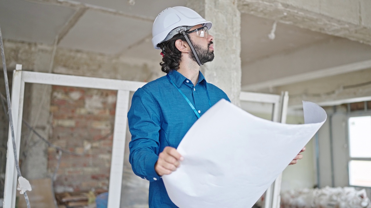 年轻的西班牙裔建筑师拿着蓝图环顾建筑工地视频素材