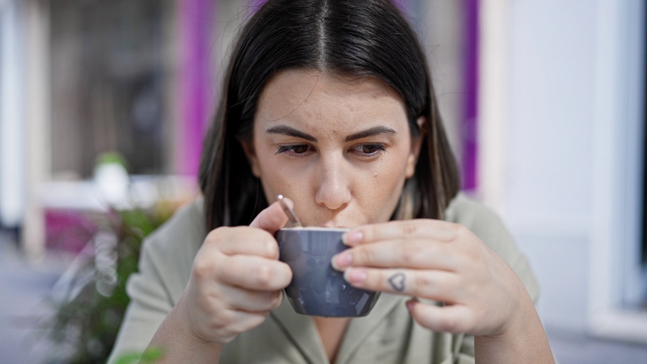 年轻美丽的西班牙女子坐在户外自助餐厅的桌子上喝咖啡视频素材