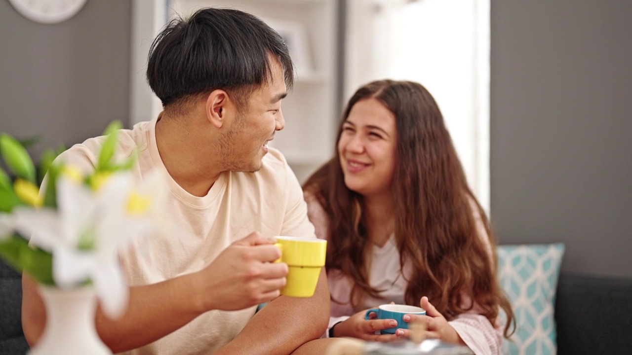 一对夫妇坐在家里的沙发上喝咖啡视频素材