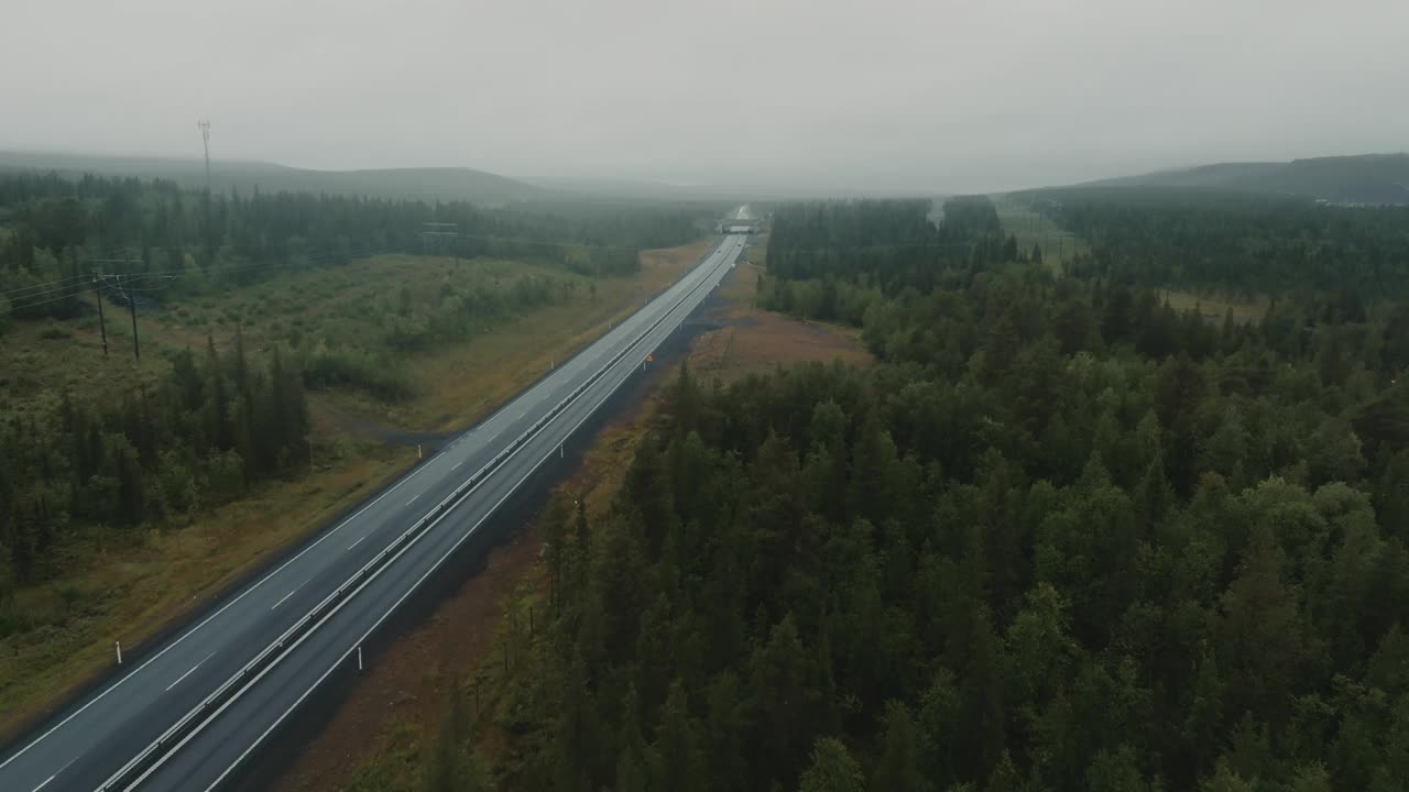 雨天行驶在森林间高速公路上的红色旅行SUV鸟瞰图视频素材