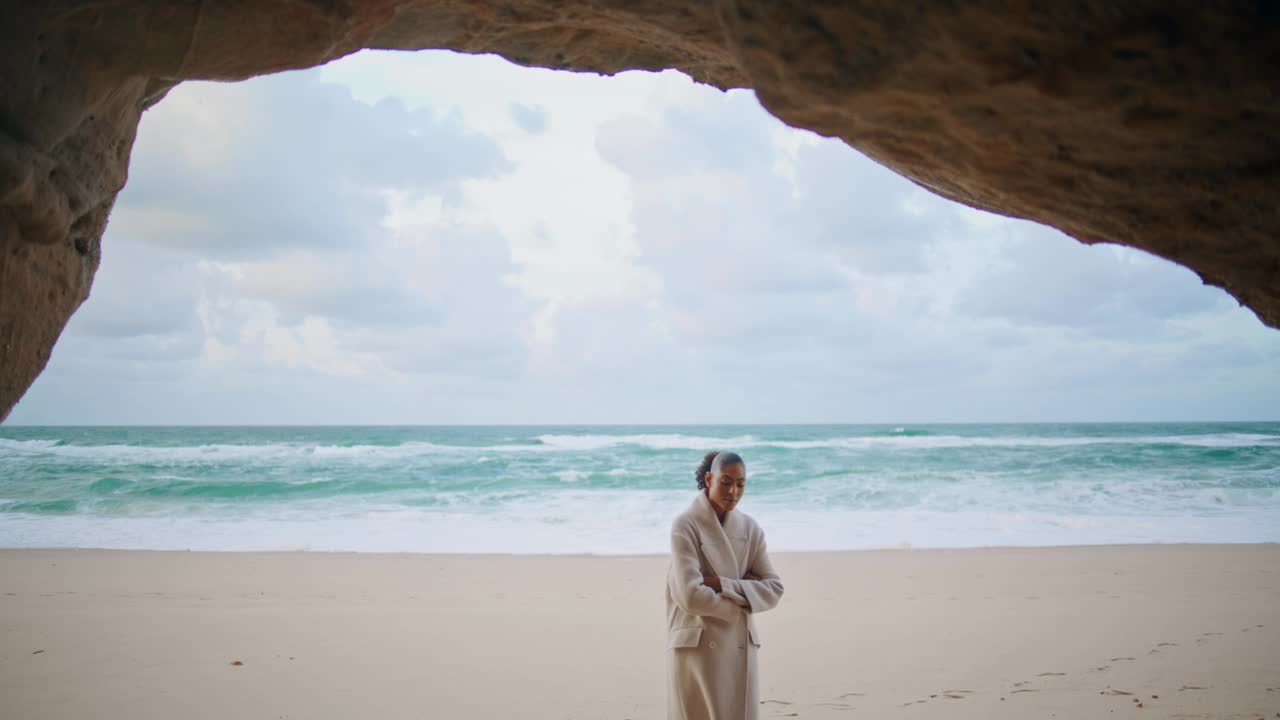 宁静的旅行者探索海滨散步的海滩。卷毛女人躲在海洋洞穴里视频素材