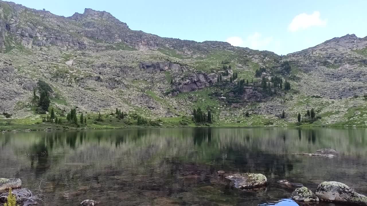 在一个阳光明媚的夏日，罕见的雨滴落在一个被山峰环绕的大湖的平坦表面上。视频素材