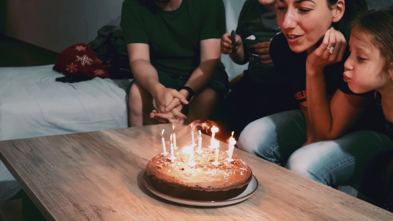 一个年轻的白人家庭在家里的沙发上用蛋糕和闪闪发光的蜡烛庆祝母亲的生日聚会视频下载