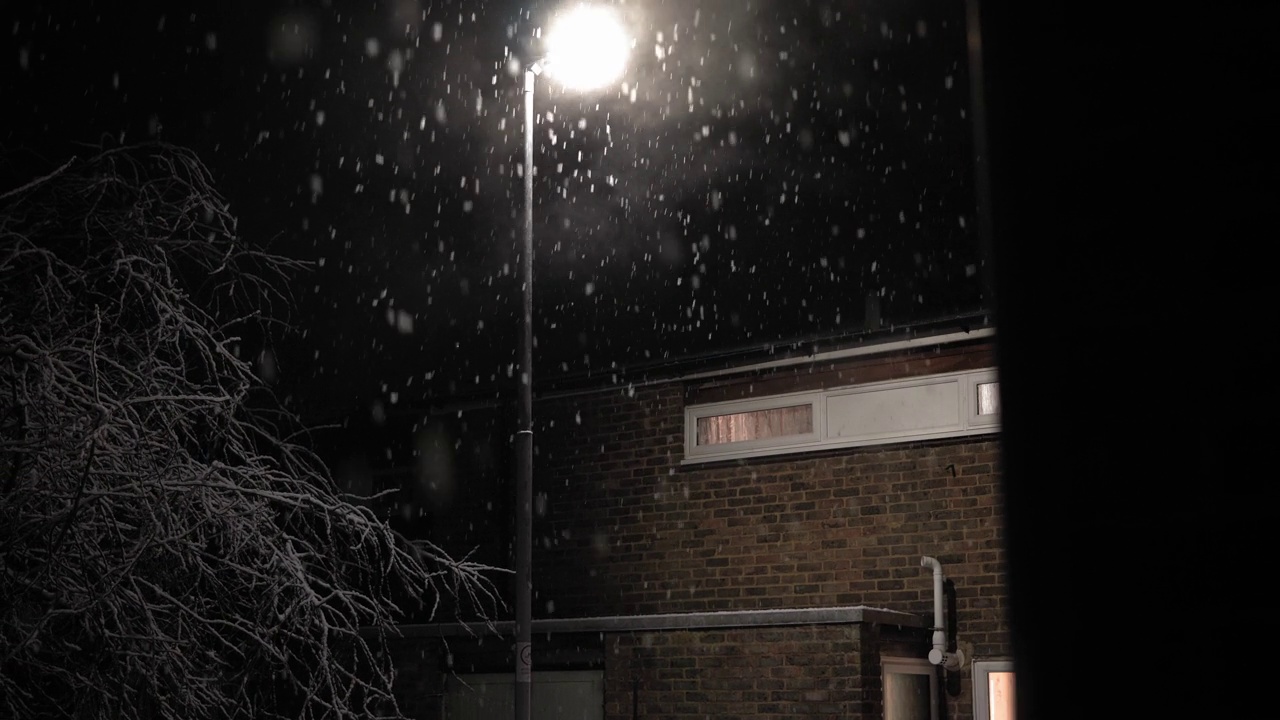 英国首次降雪叠加黑色背景。夜路路灯下的雪花-冬天，慢慢飘落的雪花效果。天气预报，异常，紧急概念视频下载