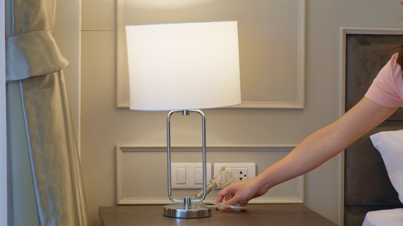 女人用手打开或关闭现代卧室里最小的灯。公寓生活理念视频素材