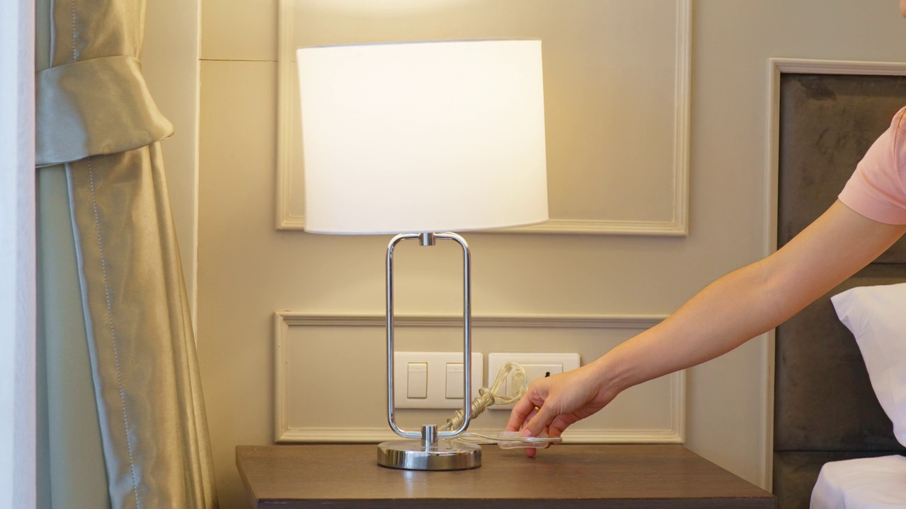 女人用手打开或关闭现代卧室里最小的灯。公寓生活理念视频素材