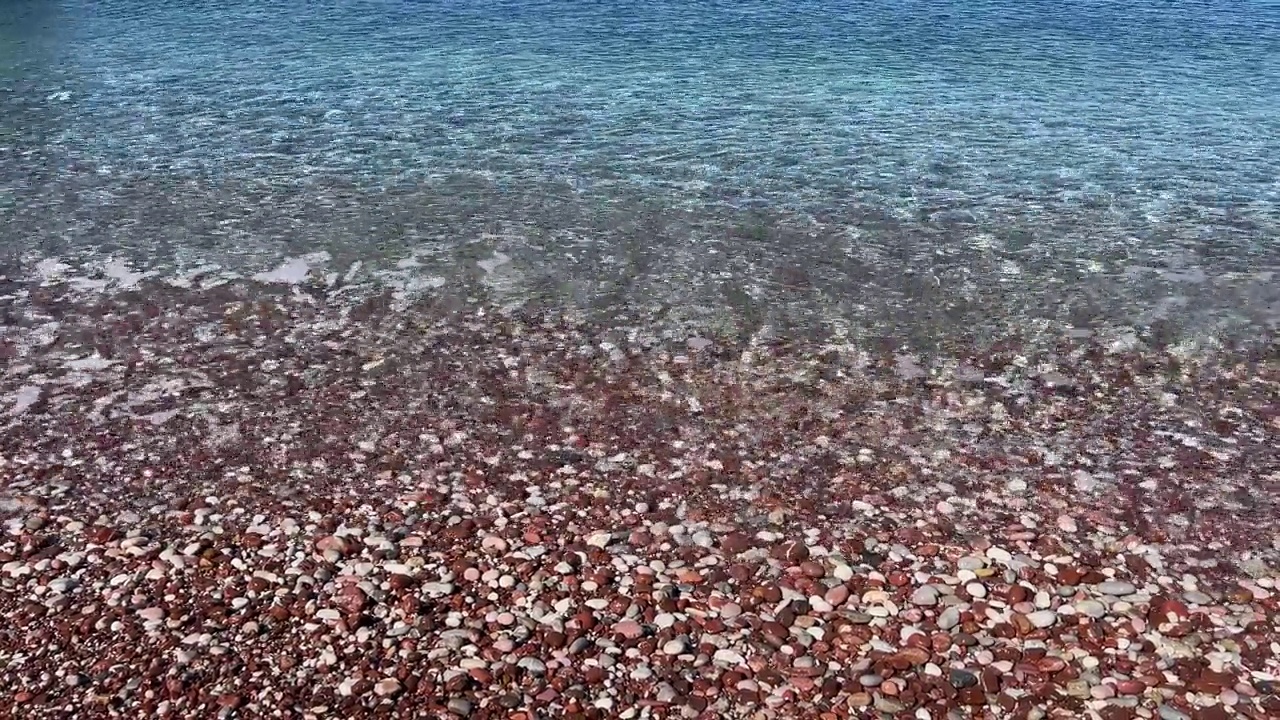 清澈的海水和粉红色的鹅卵石在亚得里亚海海岸的海滩，Sveti Stefan。视频素材