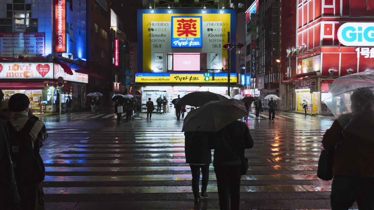 日本人在秋叶原东京使用雨伞行走过马路、骑自行车、通勤交通等夜间交通工具。都市生活、娱乐区、亚洲旅游或亚洲旅游视频下载