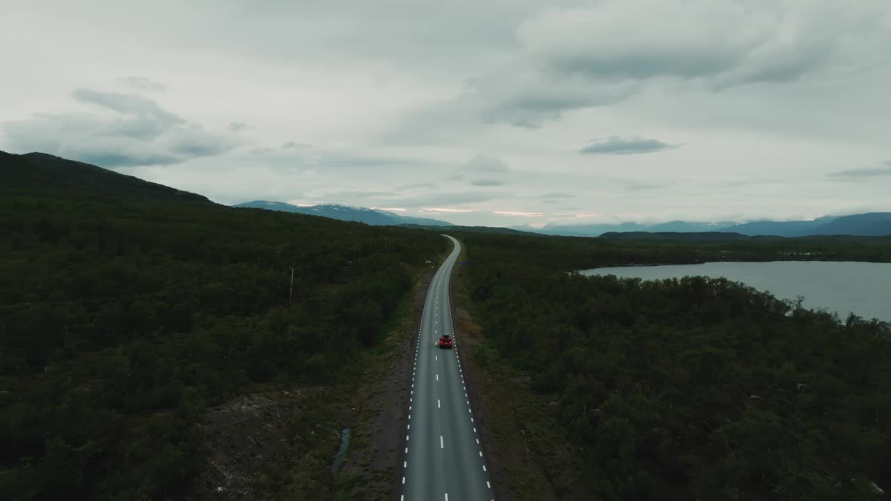 在北欧风景如画的空旷道路上行驶的红色SUV汽车的鸟瞰图视频素材