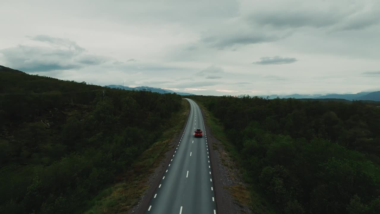 红色越野车独自行驶在空旷的车道上，绿色的北欧风景视频素材