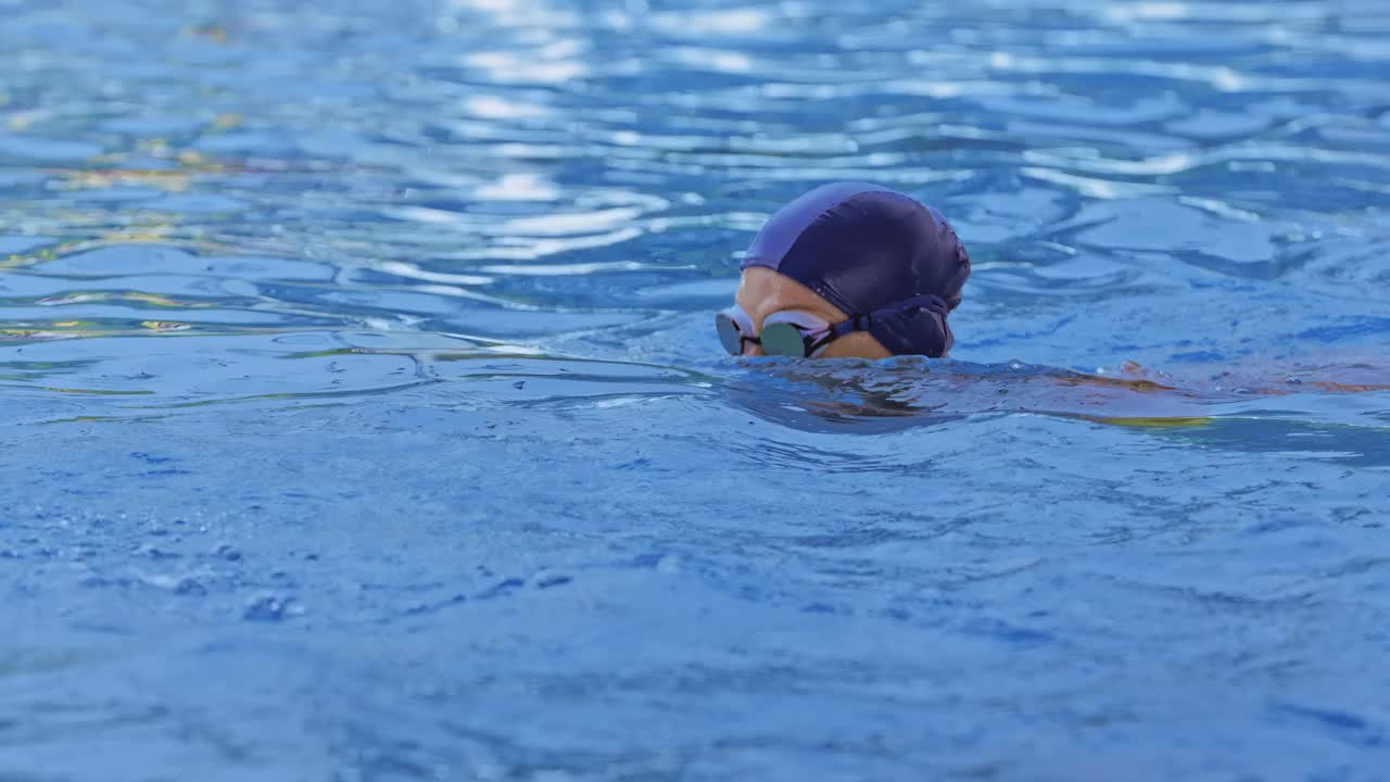 一名职业女游泳运动员在泳池边戴着护目镜的侧视图。一位女游泳者跳入水池。特写，慢镜头。视频下载