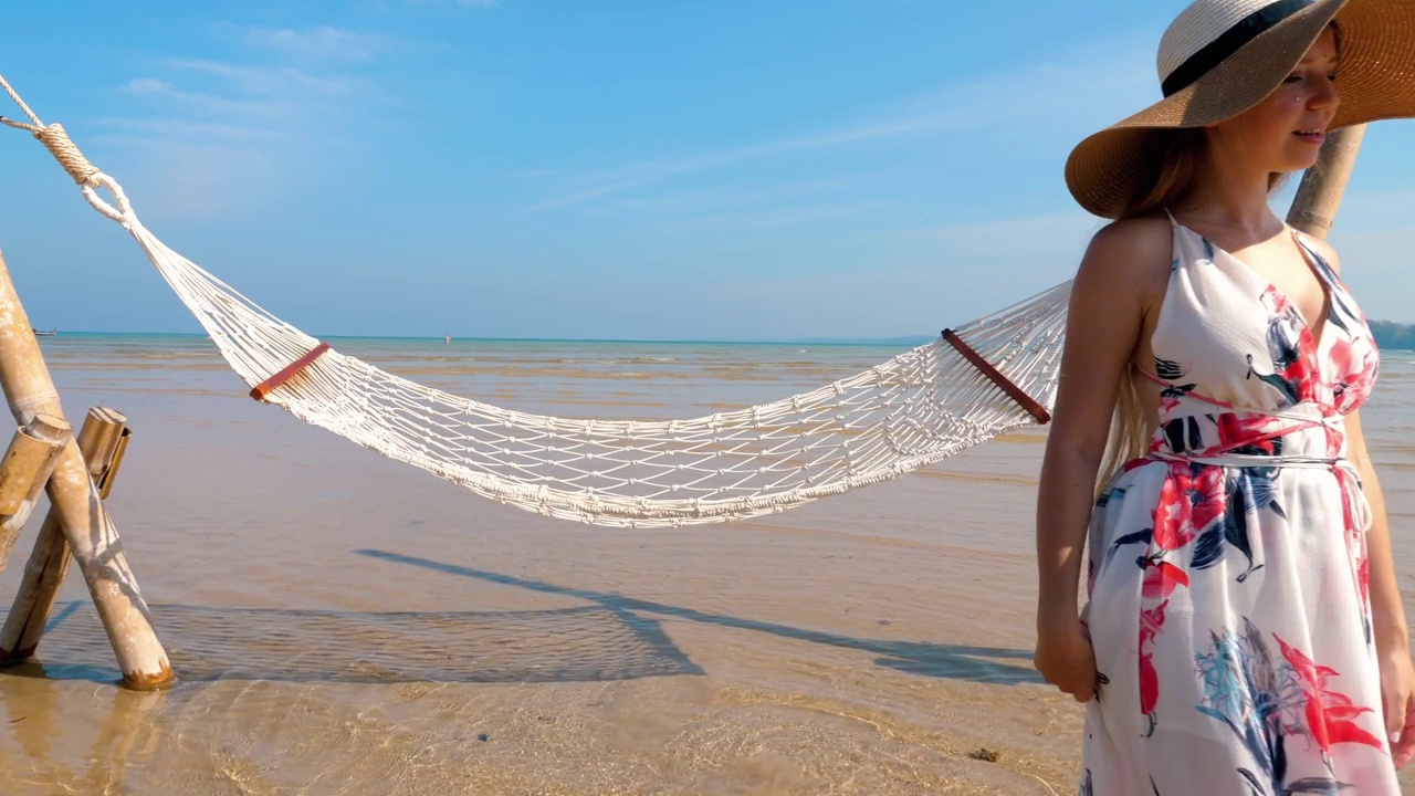 幸福的女人站在躺椅吊床在海边视频素材