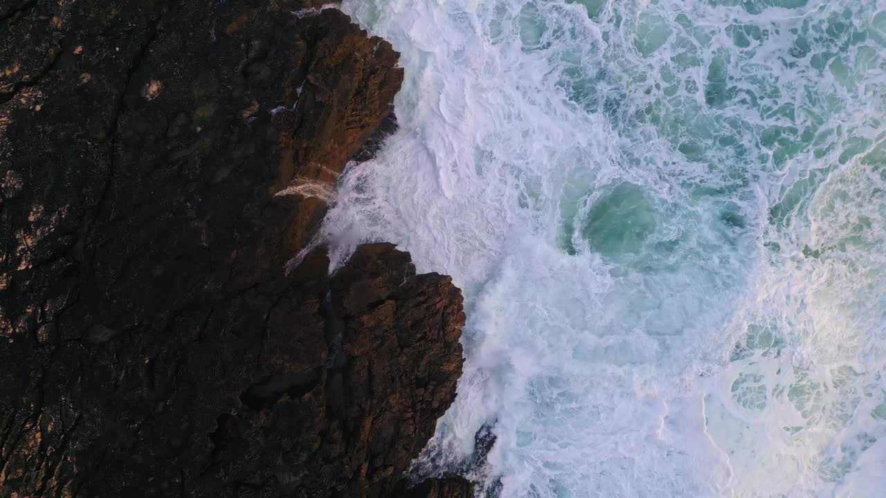 汹涌的浪花溅在危险的岩石上。空中波涛汹涌的海水。视频素材