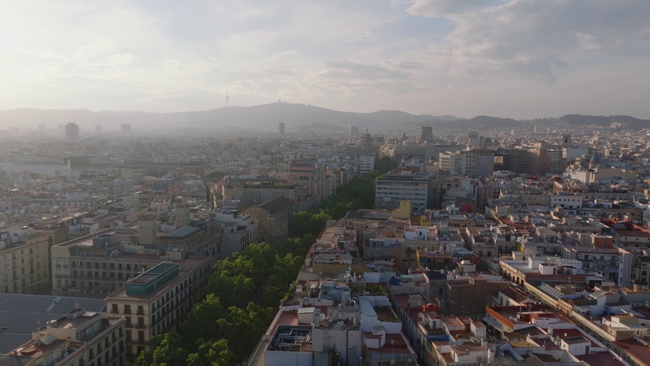 在历史城区上空飞行。黄金时刻，朦胧的景色映衬着阳光。背景是山上电视塔的剪影。西班牙巴塞罗那视频素材