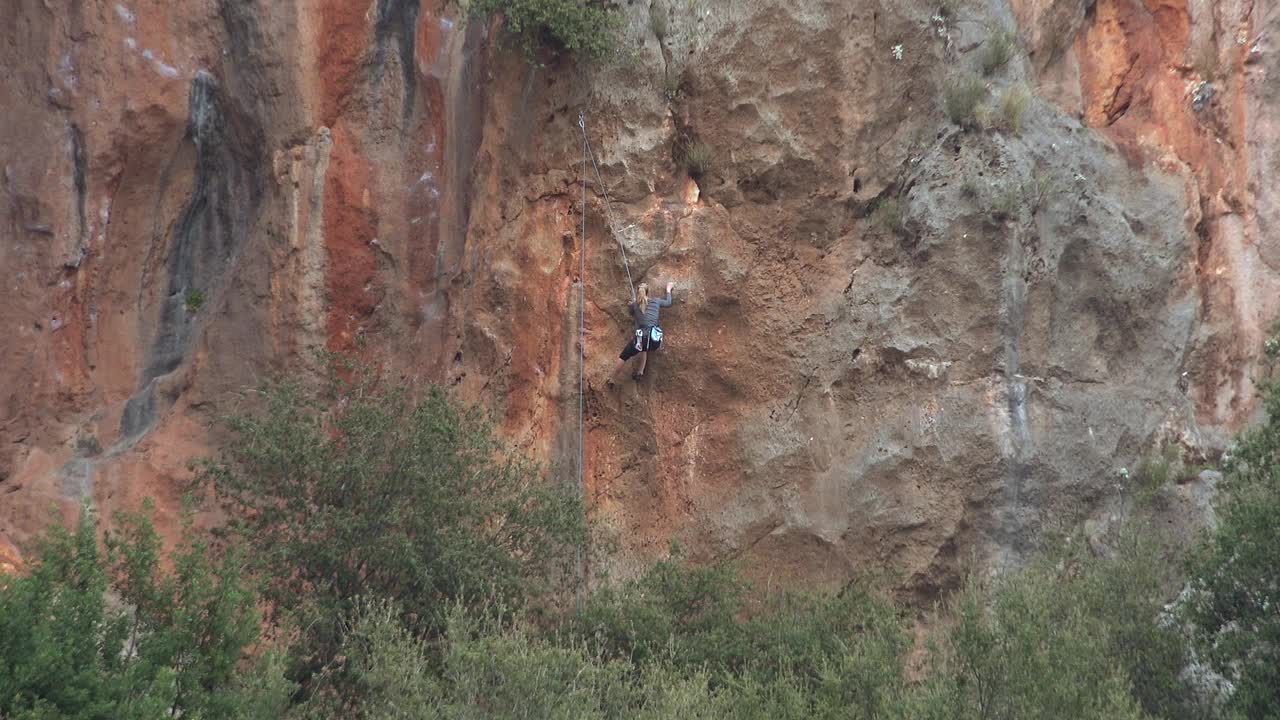 登山者在高山自然的高岩壁上攀岩的鸟瞰图视频素材