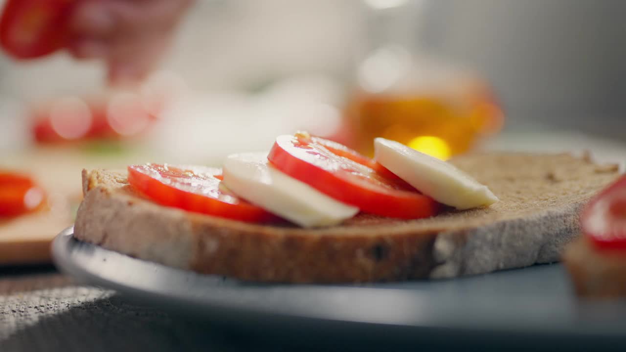 煎面包，一个白人女孩勤奋地在厨房里摆上番茄和奶酪片。慢视频素材