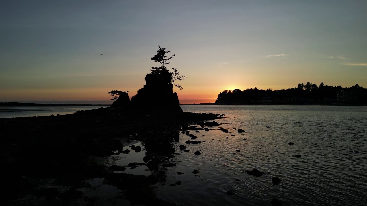 远处的山石和树木的剪影在海边与黄昏夕阳的天空视频素材