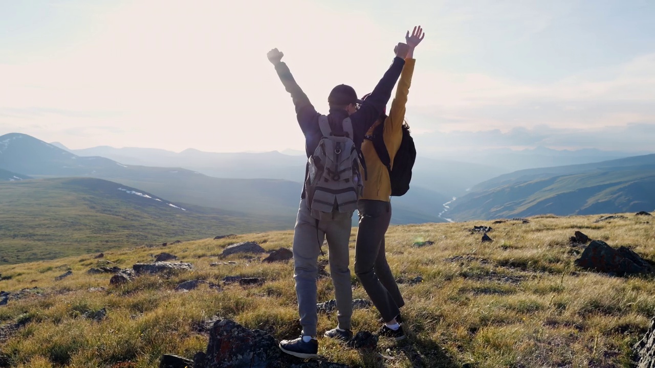 徒步旅行者夫妇一起举起手臂，高高兴兴地站在山区视频素材