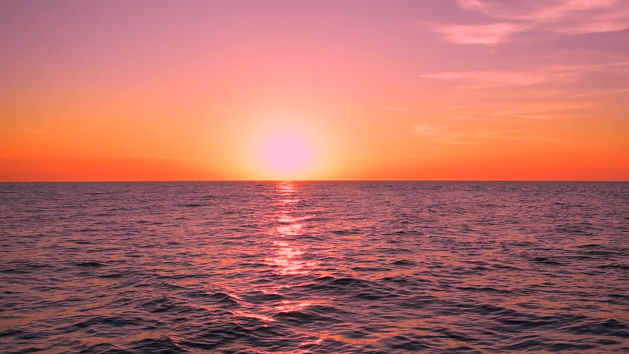 美丽的海浪反射着紫色和粉红色的夕阳。红色天空上的彩云，平静的地平线景色，海景，晴天，自然，太阳，阳光，海滩，户外，黄昏，静态拍摄，广角拍摄，慢动作。ProRes 422 HQ。视频素材