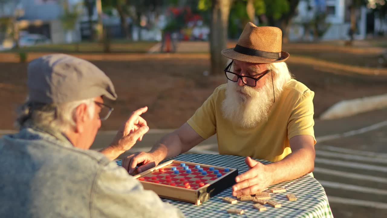 老人和他的朋友在公园里玩跳棋视频素材