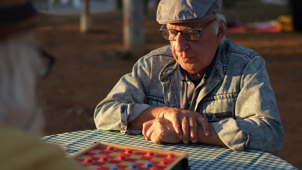 老人和他的朋友在公园里玩跳棋视频素材