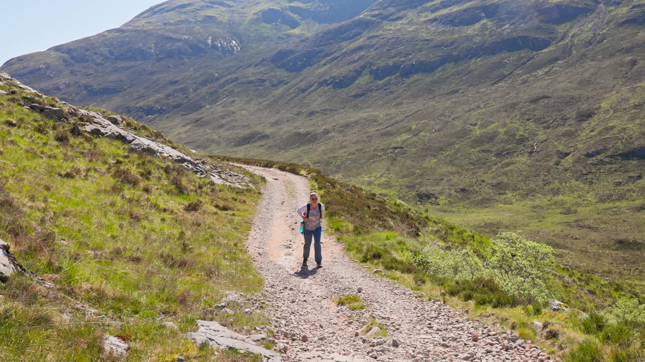 慢动作的前视图徒步旅行者走在西高地的道路上被苏格兰的草山包围视频素材