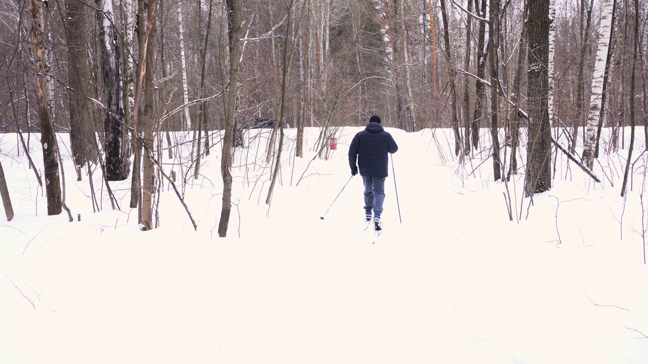 一个50岁的男人冬天在森林里滑雪视频素材