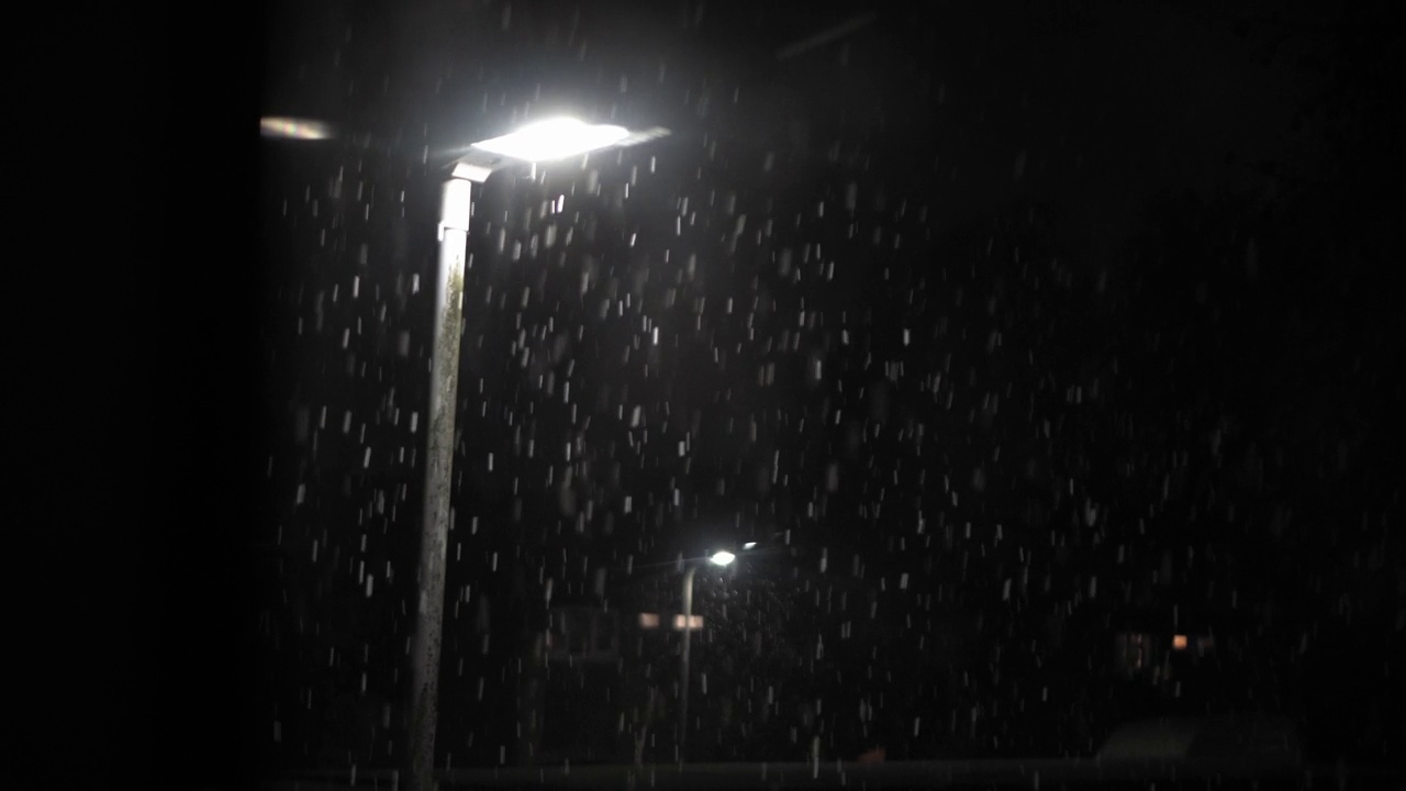 英国首次降雪叠加黑色背景。夜路路灯下的雪花-冬天，慢慢飘落的雪花效果。天气预报，异常，紧急概念视频下载