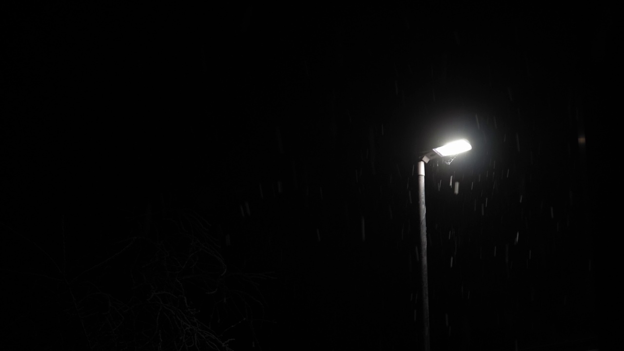 英国首次降雪叠加黑色背景。夜路路灯下的雪花-冬天，慢慢飘落的雪花效果。天气预报，异常，紧急概念视频下载