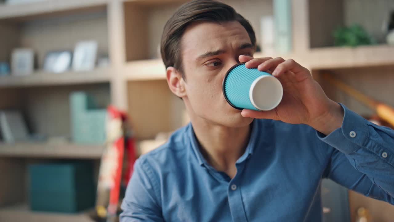 过度劳累的自由职业者喝咖啡的工作场所特写。戴眼镜的男人视频素材