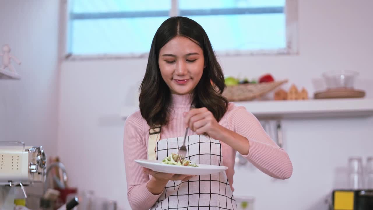 年轻迷人的亚洲女性在厨房里吃沙拉和蔬菜，饮食和健康的食物理念视频素材