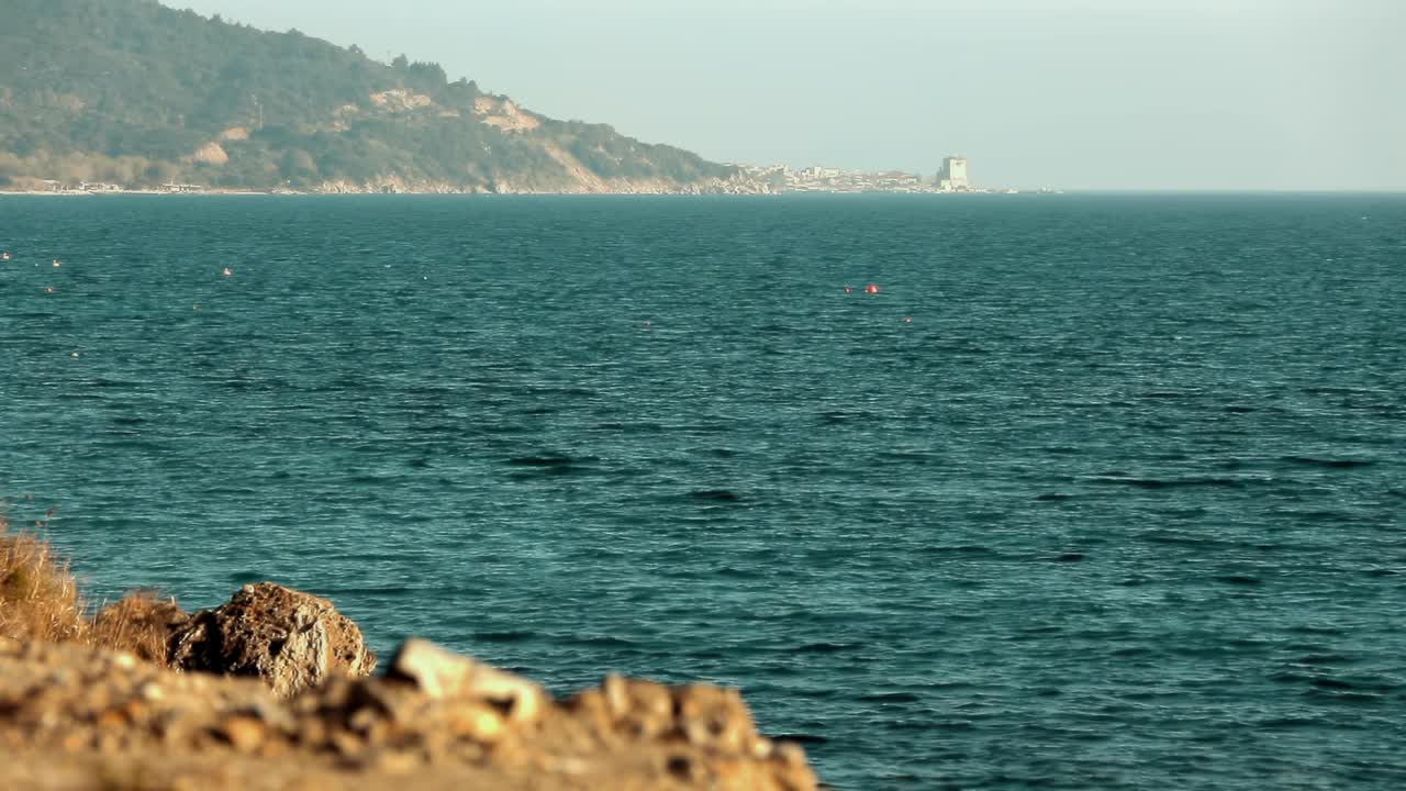 小石头后面的海景。远处是希腊城市乌拉努波利。视频下载