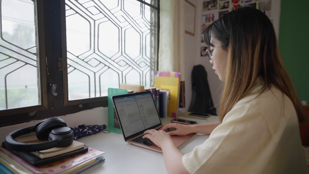 年轻的女学生在她的房间里用笔记本电脑学习视频素材