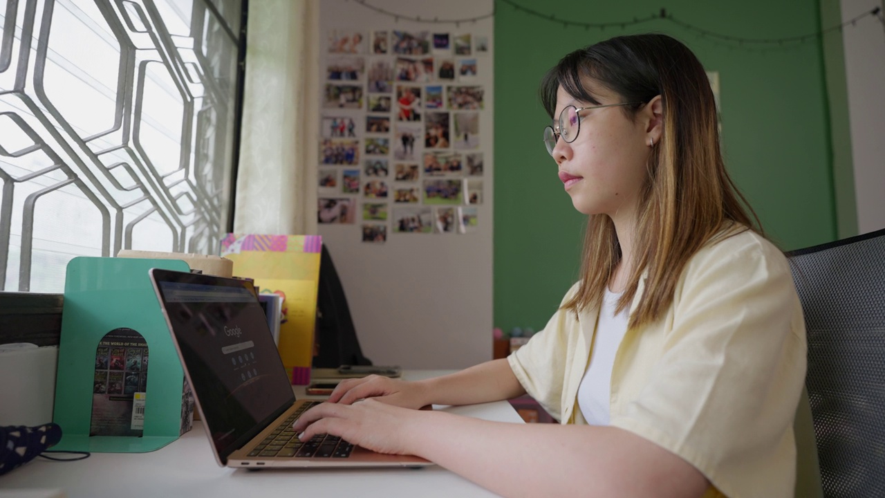 年轻的女学生在她的房间里用笔记本电脑学习视频素材