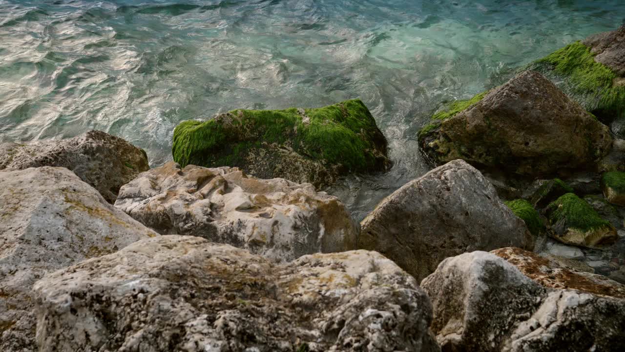 海浪翻滚到岩石海滩上的慢动作镜头，海藻和藻类提供了自然和纹理的背景视频素材