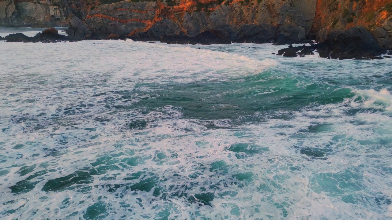 泡沫的海浪翻滚的石头海岸线特写。海水冲刷着空旷的岩石海岸视频素材