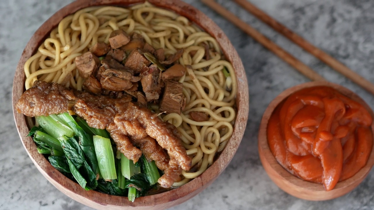 印尼鸡肉面叫mie ayam，上面有鸡肉和绿芥末，盛在碗里，配上红辣酱视频素材