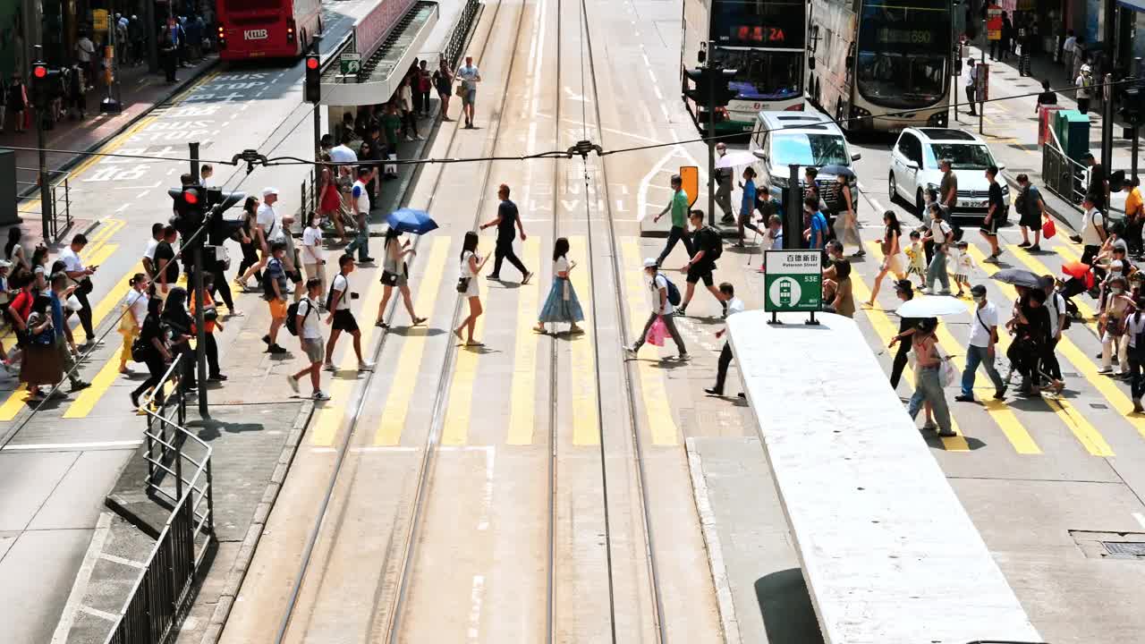 在香港铜锣湾购物区，中国人和亚洲游客走过斑马线。电车、公共汽车、汽车等交通工具。亚洲交通城市生活，香港旅游理念视频素材