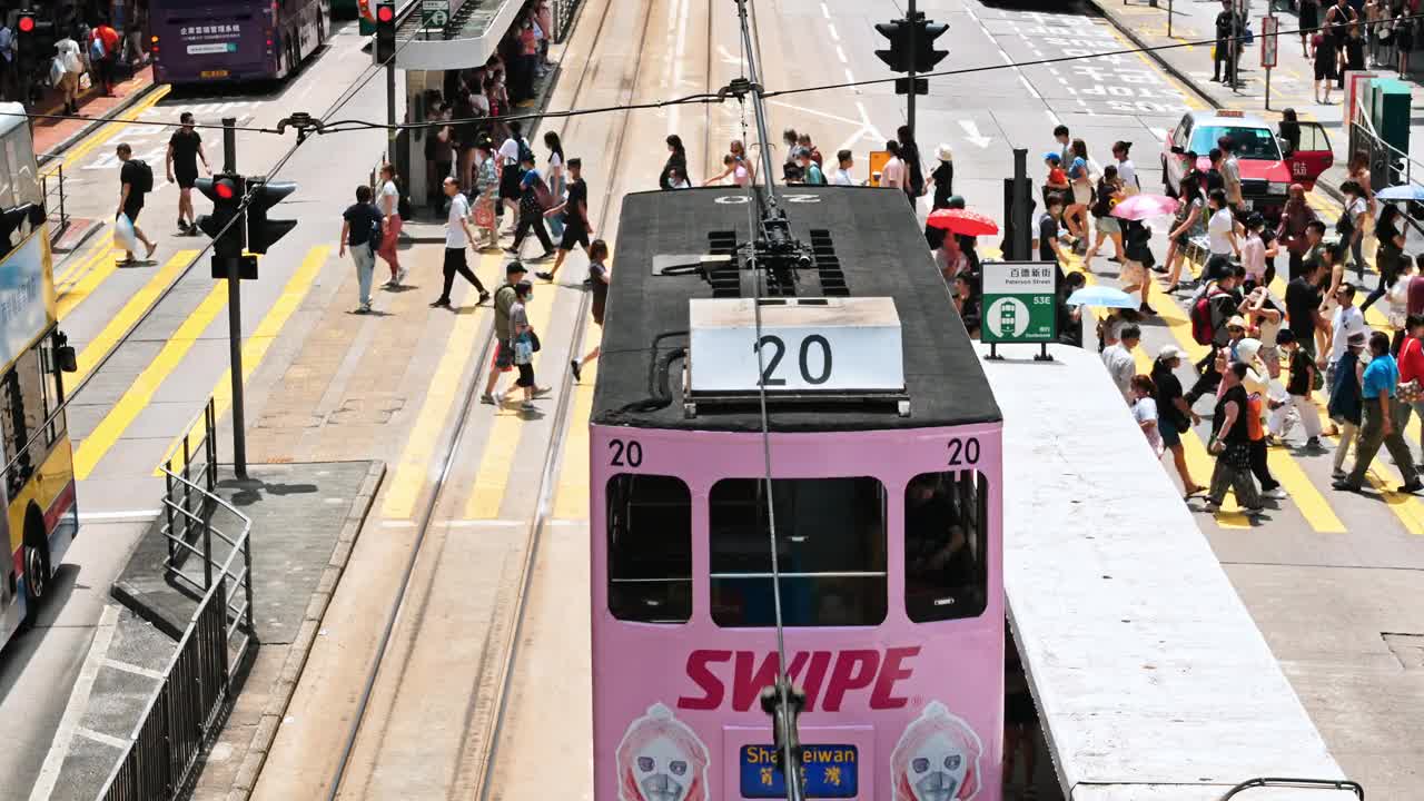 在香港铜锣湾购物区，中国人和亚洲游客走过斑马线。电车、公共汽车、汽车、出租车等交通工具。亚洲交通城市生活，香港旅游理念视频素材