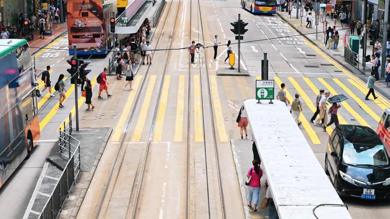 在香港铜锣湾购物区，中国人和亚洲游客走过斑马线。电车、公共汽车、汽车等交通工具。亚洲交通城市生活，香港旅游理念视频素材