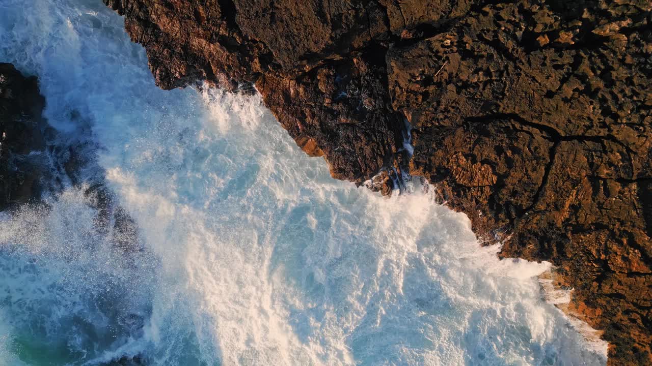 俯视图，泡沫海洋撞击海岸岩石，在慢动作中产生泡沫视频素材