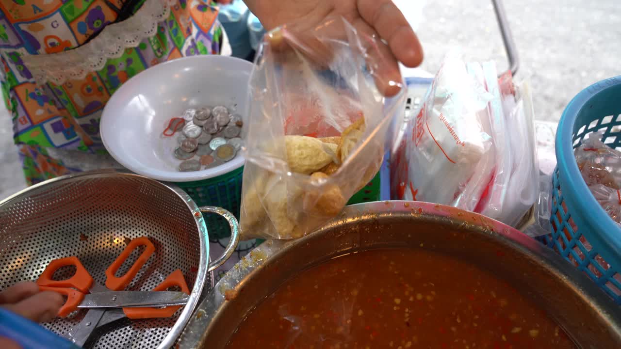 泰国街头小吃:油炸肉丸当地女商贩正在用大锅煮油煎肉丸出售。视频素材