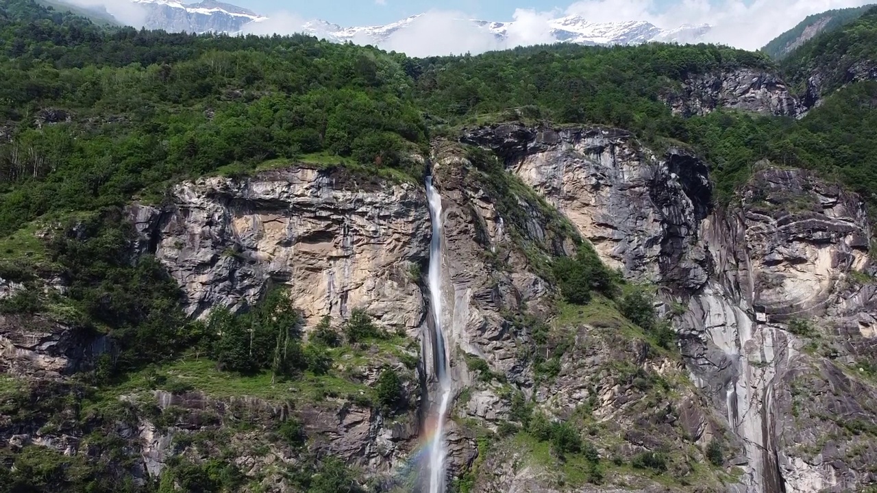 空中无人机拍摄的瀑布Cascata Di Novalesa从覆盖着绿色森林的岩石之间落下视频下载