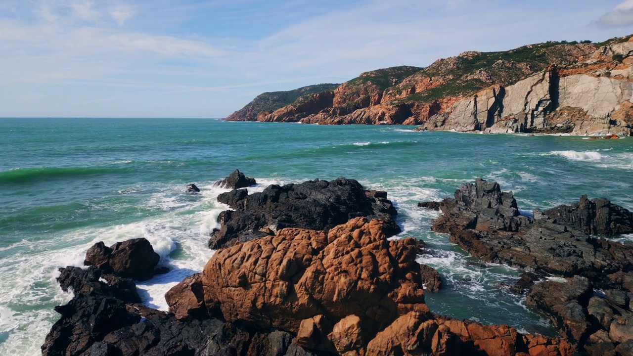 狂暴的海浪拍打着粗糙的海岸悬崖。空中滨岩视频素材