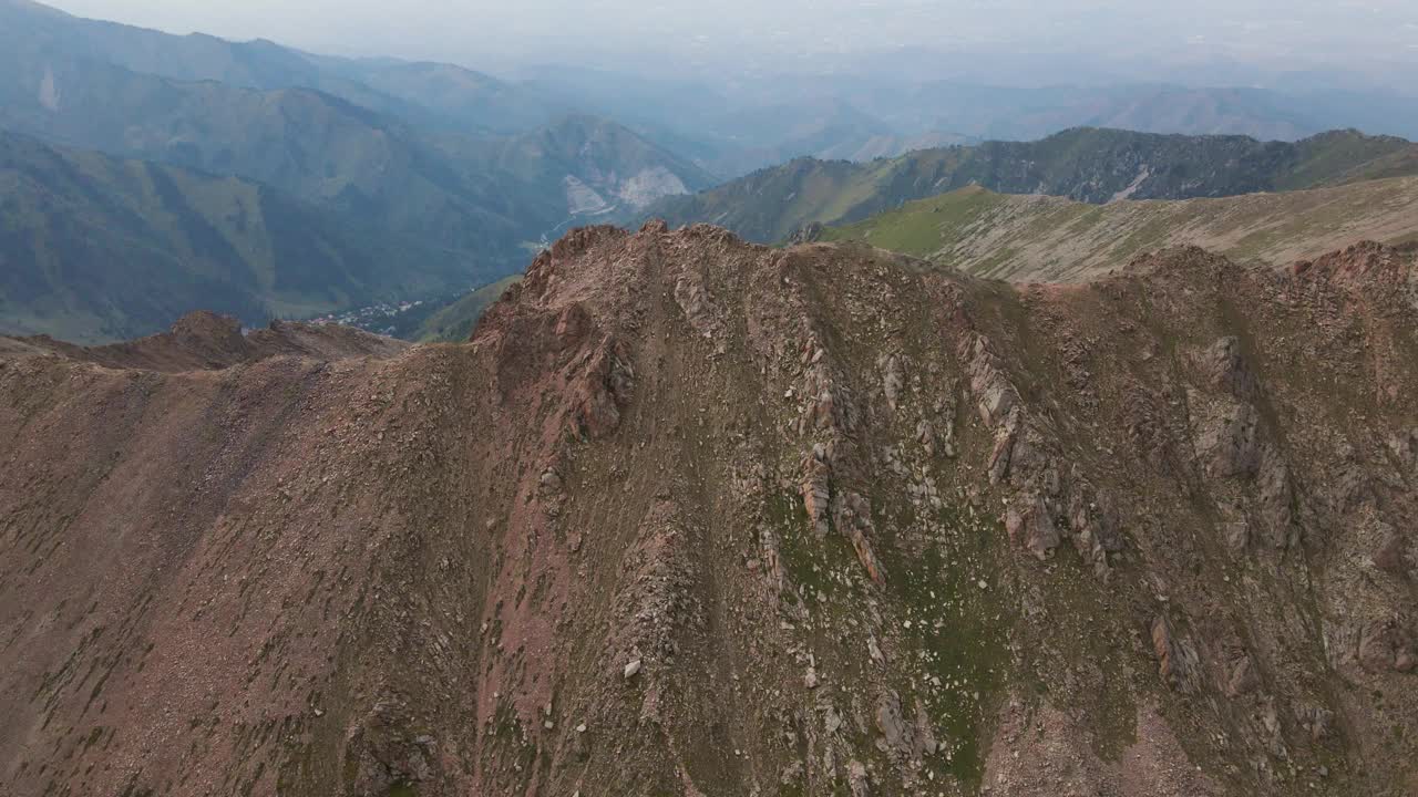 经过一座岩石山峰，背景是绿色的山丘视频下载