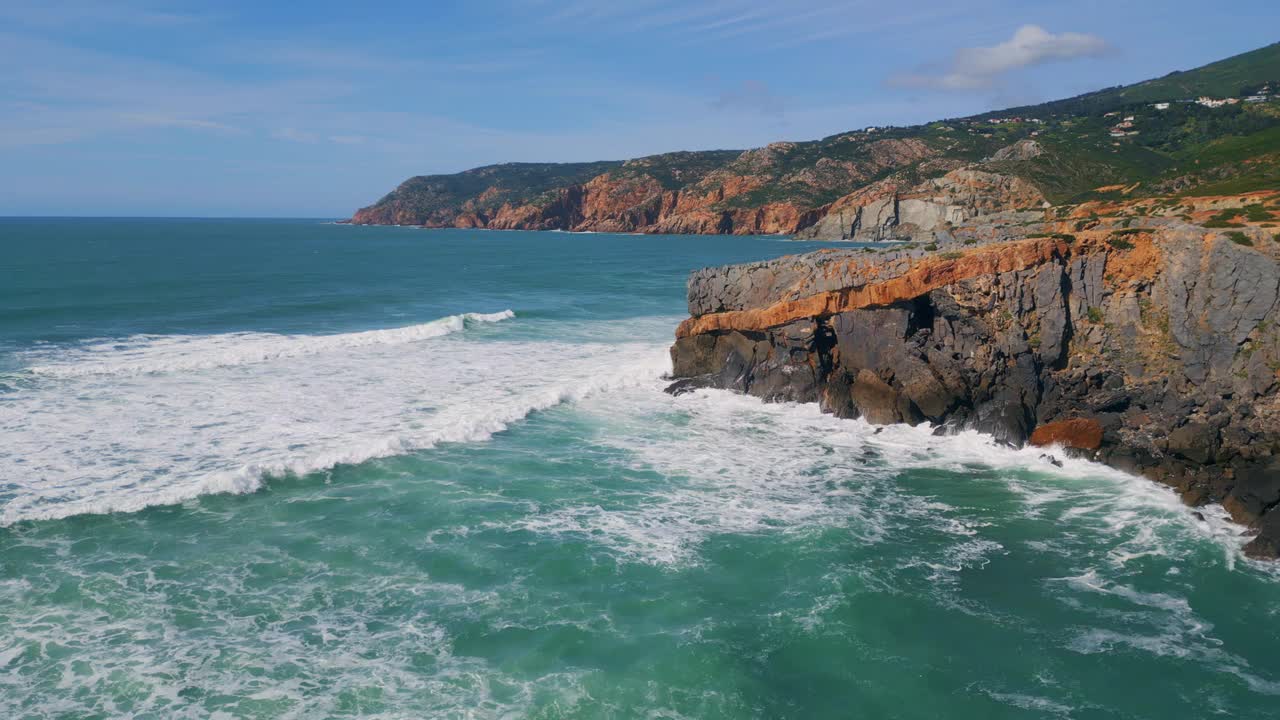 海上撞击崎岖的海岸悬崖阳光明媚的日子。汹涌的海浪拍打着岩石。视频素材