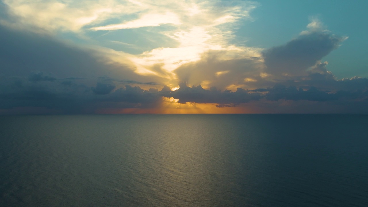 太阳沉入地平线下的迷人场景，在宁静迷人的日落中，在广阔的海洋上投射出绚丽多彩的光芒视频素材